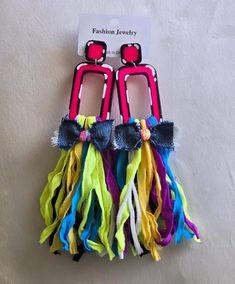 two pairs of colorful earrings with bows hanging from it's sides on a white surface