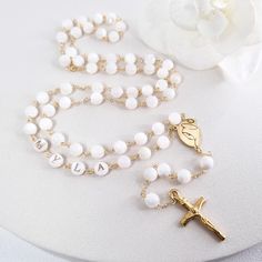 This Personalized Rosary, is ideal as a Baptism gift for a little girl or baby boy or as a gift for a special occasion. It is expertly handcrafted in a traditional style with a contemporary twist utilizing genuine Mother of pearl stone and gold-plated brass wire, which not only gives a touch of nature but also tenderness. The letter beads on the Rosary are also handmade from genuine mother of pearl, and the length is perfect to worn as a dainty Rosary necklace for women. *MATCHING ROSARY BRACELE Pearl White Rosary With 8mm Beads As Gift, Customized White Wedding Necklaces, Pearl White Spiritual Rosary As Gift, Spiritual Pearl White Rosary Gift, Spiritual Pearl White Rosary As Gift, Customized White Wedding Necklace, Beaded Cross Jewelry For First Communion, Cross-shaped Beaded Jewelry For First Communion, Adjustable White Rosary For First Communion