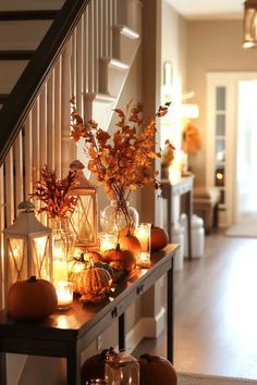 candles and pumpkins are arranged on the table in front of the staircase leading up to the entryway