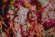 two people are smiling and confettiing each other with petals in the air