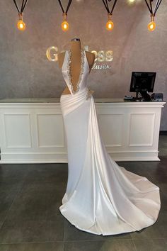 a white wedding dress on display in front of a wall with lights hanging from it