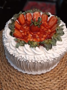 a white cake topped with strawberries on top of a wicker tablecloth covered plate