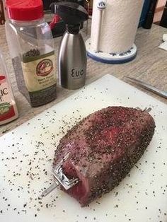 a steak on a cutting board with spices and seasoning next to it, ready to be cooked