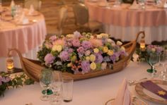 there is a boat decorated with flowers and candles on the table at this wedding reception