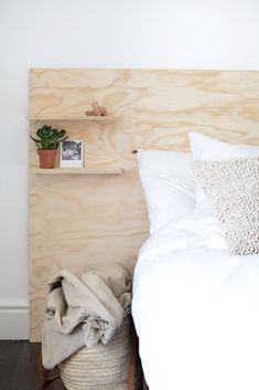 a bed with white linens and pillows in a bedroom next to a wooden headboard