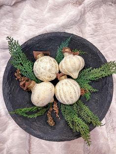 a black plate topped with white balls and pine cones on top of a fur covered floor