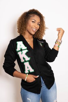 a woman with curly hair wearing a black cardigan sweater and jeans, posing for the camera