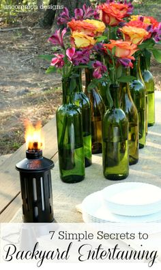 seven simple secrets to backyard entertaining with flowers in green glass bottles on a picnic table