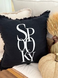 a black and white pillow sitting on top of a wooden bench next to a pumpkin