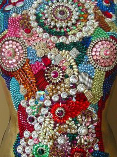 the back of a woman's dress covered in lots of colorful beads and jewels