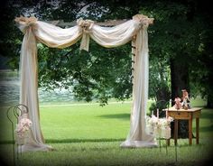 an outdoor wedding setup with white drapes and flowers