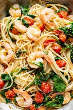 pasta with shrimp, spinach and tomatoes in a white bowl