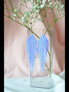 a vase filled with flowers and tassels on top of a white table cloth