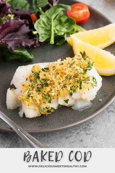 a plate filled with fish and vegetables on top of a table next to lemon wedges