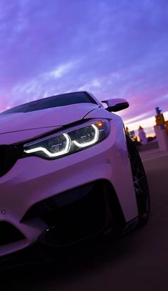 the front end of a purple car with its lights on