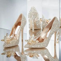 a pair of high heeled shoes with pearls and bows on the heels are shown in front of a mirror