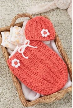 an orange crochet baby set in a basket on the floor next to a blanket