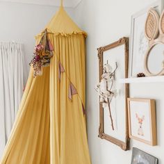 a yellow tent hanging from the side of a wall in a room with pictures on it