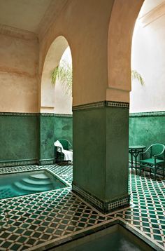 an indoor swimming pool surrounded by green chairs