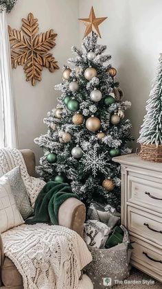 a white christmas tree with green and gold ornaments in a living room setting, surrounded by other holiday decorations