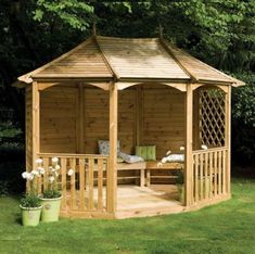 a wooden gazebo sitting on top of a lush green field