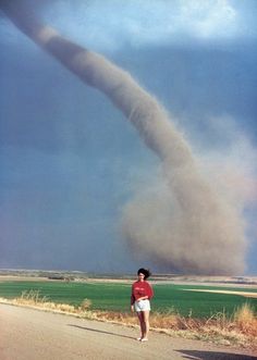 a man is walking down the road with a large object in the sky