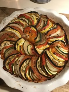 a white dish filled with sliced vegetables on top of a wooden table