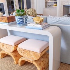 a white table with two stools and a potted plant on top of it