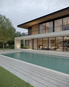 a house with a pool in front of it and large glass windows on the side