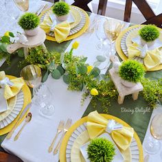 the table is set with yellow and white plates, napkins, and green centerpieces