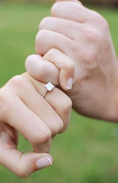 a woman holding the hand of a man with a diamond ring on his finger in front of her