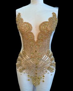 a white mannequin with gold sequins on it's chest and back