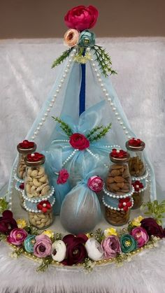 an arrangement of nuts and flowers on display in a basket with blue ribbon tied around it