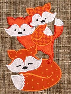 three little foxes are sitting on top of each other, one is red and the other is white