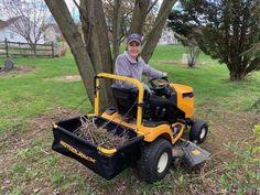 a man sitting on top of a yellow lawn mower