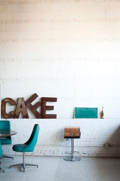 there is a cake sign on the wall above two chairs and a table in front of it