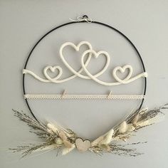 two hearts are hanging on the wall above wheat stalks and an iron hoop with twine