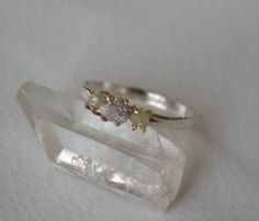 two gold and silver rings sitting on top of a clear quartz block with white background