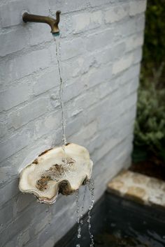 a faucet that is attached to the side of a building with water running from it