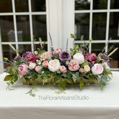 an arrangement of flowers on a table in front of a window