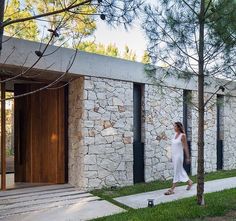 a woman walking down the sidewalk in front of a stone building