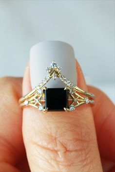 a woman's hand holding a ring with a black stone and diamonds on it