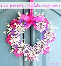 a snowflake wreath is hanging on the front door with pink and purple decorations