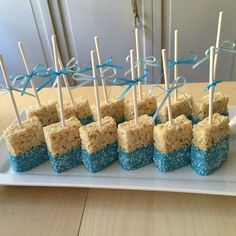 rice krispy treats with toothpicks are arranged on a white platter, ready to be eaten