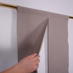 a person is holding the edge of a curtain