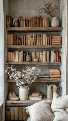 a bookshelf filled with lots of books next to a white couch and pillows