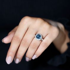 a woman's hand with a ring on her finger and a blue stone in the middle