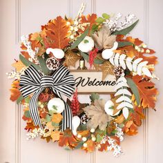 a welcome wreath is hanging on the front door with leaves and acorns around it