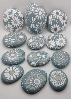 painted rocks with white flowers on them are arranged in a circle and placed next to each other