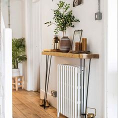 a wooden shelf with plants and candles on it in front of a wall mounted radiator